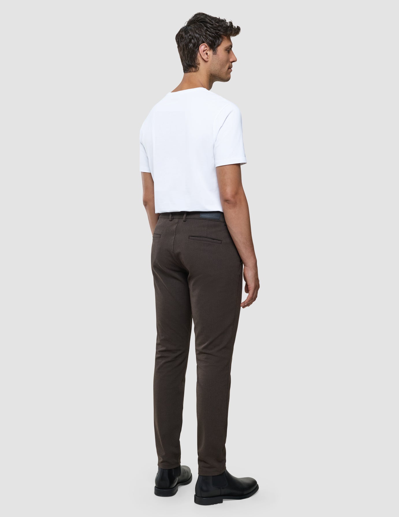 Gen2 Slim i Signature Brown, mand set bagfra i hvid t-shirt og brune bukser.